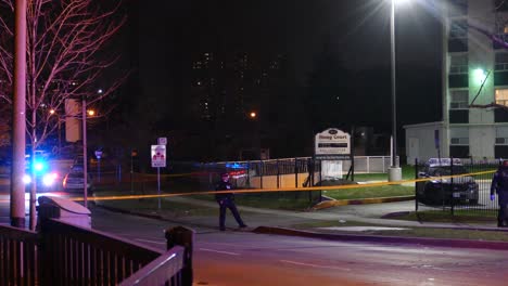 Police-tape-in-front-of-crime-scene-at-night-in-apartment-building,-Toronto,-Canada,-static-wide-shot