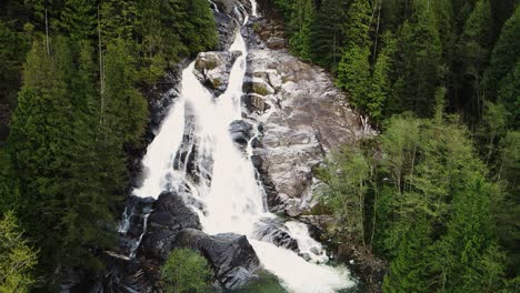 Slow-pullback-aerial-shot-of-Silver-Falls-waterfall-in-a-forest-in-Deep-Cove,-Vancouver,-Canada