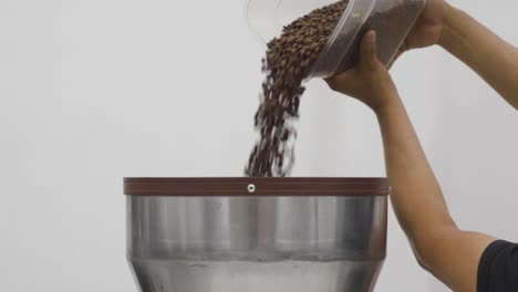 Man-Fills-The-Funnel-Of-Coffee-Grinder-With-Coffee-Beans