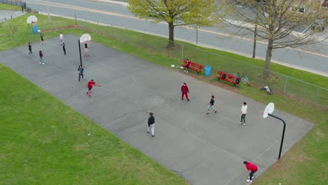 Aerial-of-male-boys-and-youth-playing-basketball-at-inner-city-court-in-America,-USA