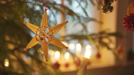 CHRISTMAS-DECORATIONS---Straw-star-hanging-on-a-Christmas-tree,-Sweden,-close-up
