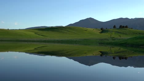 Reflection-of-rolling-hills-and-trees-on-calm-water-surface