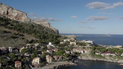Sunny-Sicilian-coastal-community-aerial,-waterfront-homes-on-point