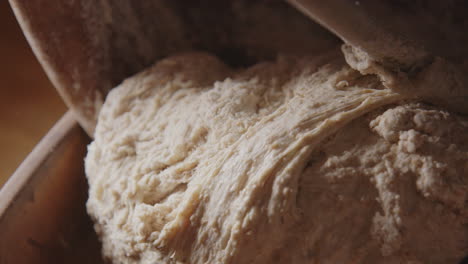 BAKING---Wooden-spoon-moving-sourdough-bread-dough,-slow-motion-tilt-down