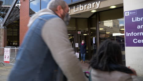 People-walking-past-and-out-of-a-local-library-after-pandemic-lockdown-measures-are-eased-in-UK