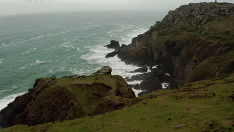 Aerial-pan-along-the-rough-coastline-of-Cornwall,-England,-revealing-ruins-of-the-tin-mines,-part-of-the-dramatic-scenery-used-in-the-Masterpiece-Theater-presentation-of-Poldark