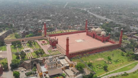 Vista-Aérea-De-Paralaje-De-La-Mezquita-Badshahi-Con-Patio-En-Lahore,-Pakistán,-Vista-De-La-Ciudad