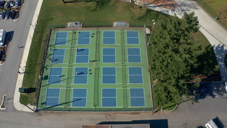 Tennis-Players-in-a-City-Park,-Drone-Truck-Left-past-the-Sports-Courts