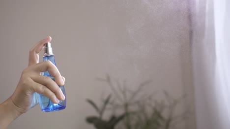 Woman-using-spray-air-freshener-indoors