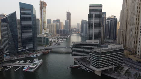 Luxury-yachts-and-construction-cranes-on-skyscraper,-Dubai-Marina,-drone