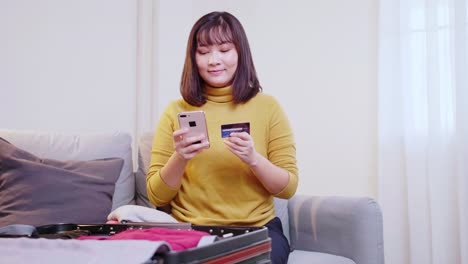 Schöne-Asiatische-Frau,-Die-Online-Einen-Flug-Mit-Ihrem-Handy-Und-Ihrer-Kreditkarte-Für-Reisen-Im-Sommer-Bucht