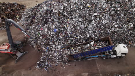 Aerial-footage-of-waste-and-scrap-metal-delivery-and-mechanical-grab-moving-metal-from-a-large-heap-of-scrap-metal