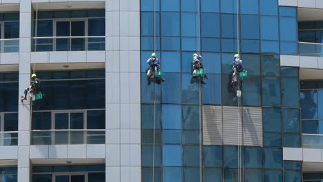 Window-Cleaners-Wash-The-Glass-On-The-Wall-Of-An-Office-Building-In-A-Skyscraper---low-angle-shot