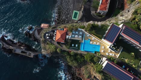 A-single-person-is-swimming-alone-in-the-blue-pool-in-the-luxury-resort-on-the-cliff-with-the-ocean-on-the-side