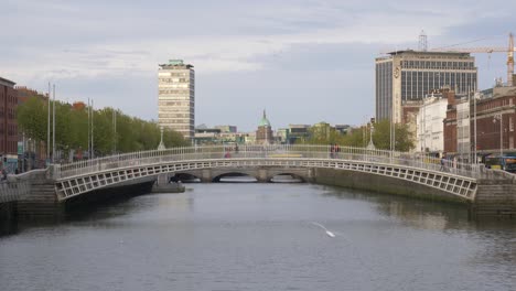 People-Cross-At-Ha'penny-Bridge-Over-Liffey-River-In-Dublin,-Ireland
