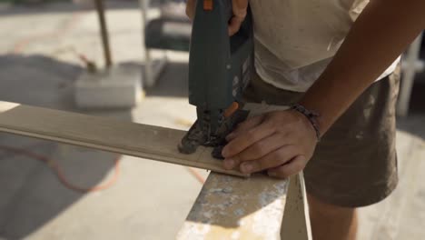 Male-carpenter-cutting-wood-with-jigsaw