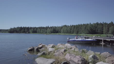 Motorboat-stopping-at-small-pier-in-Finnish-archipelago-region,-tilt-down-view