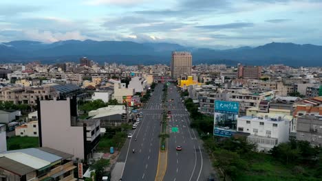 Imágenes-De-Hiperlapso-De-Drones-Aéreos-A-Vista-De-Pájaro-De-La-Ciudad-De-Doliu-En-Taiwán-Con-Una-Carretera-Recta-Como-Línea-Principal-Hacia-Las-Hermosas-Montañas-Azules-Y-El-Cielo