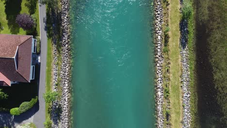Vibrant-turquoise-green-glacier-river-in-Loen---Steady-flow-of-water-from-melted-ice---Showing-river-banks-and-walkway---Slowly-upstream-forward-moving-birdseye-aerial---Norway