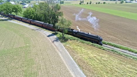 A-Drone-View-of-a-Steam-Locomotive-With-Passenger-Coaches-Approaching-over-Countryside-on-a-Beautiful-Summer-Day