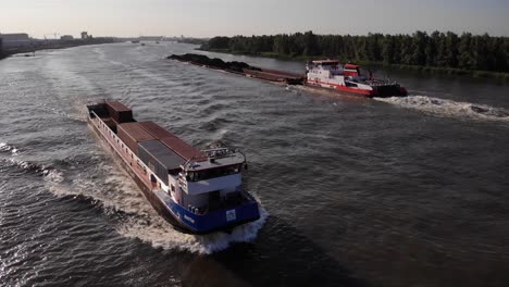 Aerial-Over-Martie-Cargo-Ship-Going-Past-Barge-Along-River-Oude-Maas