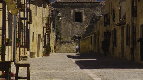 People-In-Masks-Exploring-Narrow-Street-With-Stone-Houses-In-Town-Of-Pedraza-In-Segovia,-Spain-During-Pandemic