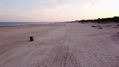 Beautiful-ascending-aerial-view-of-a-long-sandy-empty-Baltic-sea-beach-at-Liepaja-after-the-sunrise,-calm-water-and-no-people,-summer-morning,-wide-angle-revealing-drone-shot-moving-forward