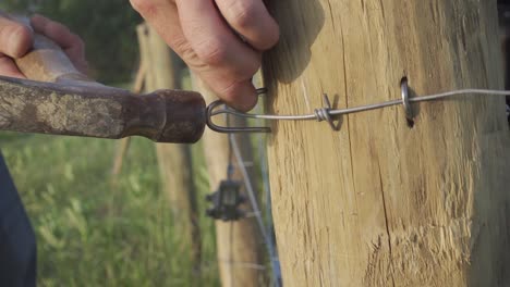 Macro-Of-A-Farmer-Pounding-Metal-Staples-On-Wire-Fence-Using-A-Hammer-Inside-The-Ranch