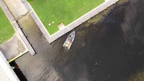 An-aerial,-top-down-drone-shot-over-a-boat-in-a-canal,-the-camera-is-looking-straight-down-and-pan-left
