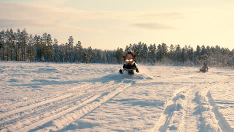 Man-on-a-Snowmobile-doing-a-jump-on-a-snowy-lake-a-sunny-winterday
