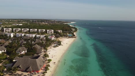 Aerial-drone-shot-view-of-a-paradise-beach-with-turquoise-clean-water-in-a-touristy-place-with-resorts-and-hotels-in-Nungwi,-Zanzibar,-Africa-4K