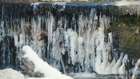 small-waterfall-in-the-frozen-river,-static-close-up,-slow-motion