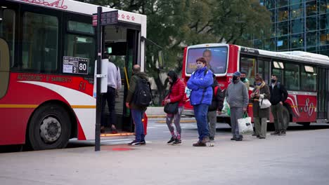 Row-of-people-with-face-mask-entering-bus-at-bus-station-in-slow-motion,Buenos-Aires