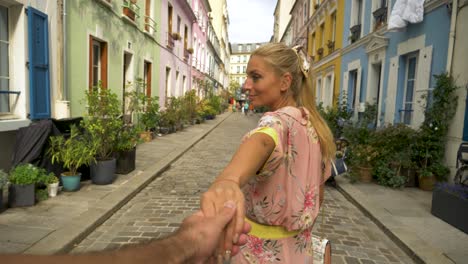 Pretty-woman-holding-hands-with-boyfriend-follows,-Rue-Cremieux,-paris