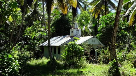 A-small-cute-old-white-church-chapel-with-cross-surrounded-by-forest-and-trees-on-a-small-remote-island-in-the-wilderness,-Nahlap-Island-in-Pohnpei,-Federated-States-of-Micronesia