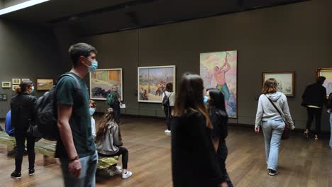 Multiple-paintings-and-tourists-inside-a-gallery-of-the-Orsay-museum-in-Paris