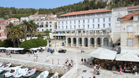 Luftaufnahme-Von-Touristen,-Die-Entlang-Des-Hafens-Von-Hvar-Mit-Restaurants-Und-Gebäuden-Am-Wasser-In-Kroatien-Spazieren