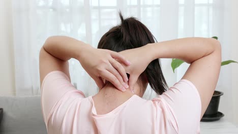 Back-view-of-Asian-woman-using-hands-to-massage-the-nape-of-her-neck-in-physical-therapy-to-reduce-pain-at-work