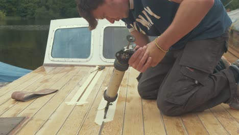 A-young-man-applying-sealant-between-wooden-boat-roof-planks