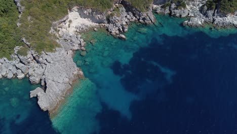 Aerial:-rocky-shore-with-forest-and-blue-sea-water-at-Lefkada,-Greece:-drone-flying-shot