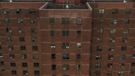 Dramatische-Luftneigung-Entlang-Der-Vertikalen-Achse-Des-Wohnprojektgebäudes-In-East-Harlem,-New-York-City,-Am-Frühen-Morgen,-Das-Die-Skyline-Enthüllt