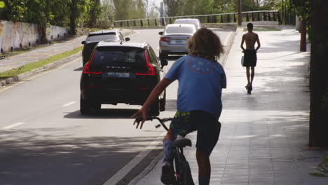 Jungen,-Die-Roller-Und-Biycle-Auf-Straßenbürgersteig-In-San-Juan,-Puerto-Rico-Reiten