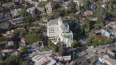 A-slow-flight-around-the-Chateau-Marmont-in-Hollywood-California-with-views-of-the-famous-swimming-pool,-Sunset-Boulevard-and-Pink-Taco-restaurant