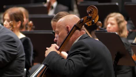 Focus-on-a-man-playing-the-cello-with-an-orchestra,-Liepāja-Symphony-Orchestra-season-opening-concert,-concert-hall-Great-Amber-,-medium-closeup-shot,-selective-focus