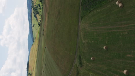 Flyover-above-hay-bales-and-farmland-around-Delnita,-Romania