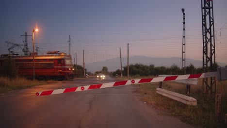 Tren-Nocturno-Pasando-Por-Carretera-Con-Barreras-Cerradas