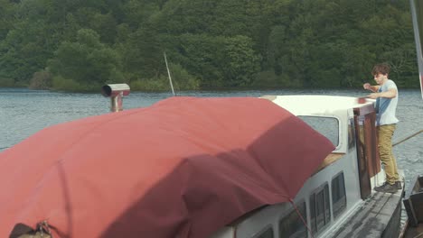 Junger-Mann-An-Bord-Eines-Holzbootes-Wischt-Staub-Vom-Hölzernen-Liveboard-Boot