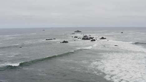 Drone-aerial-over-choppy-ocean-waves-toward-a-fishing-boat-in-the-distance-on-a-cloudy-day,-Pacific-ocean,-Oregon