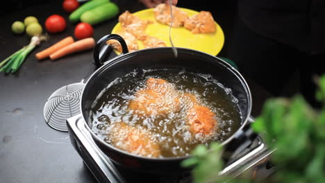 Turning-upside-down-the-fried-chicken-pieces-with-a-fork-while-frying-in-a-deep-pan