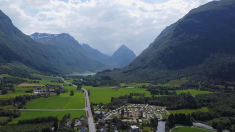 Village-and-valley-in-Byrkjelo-with-pointy-mountain-Eggjenibba-in-background---Reverse-summer-day-aerial-Norway